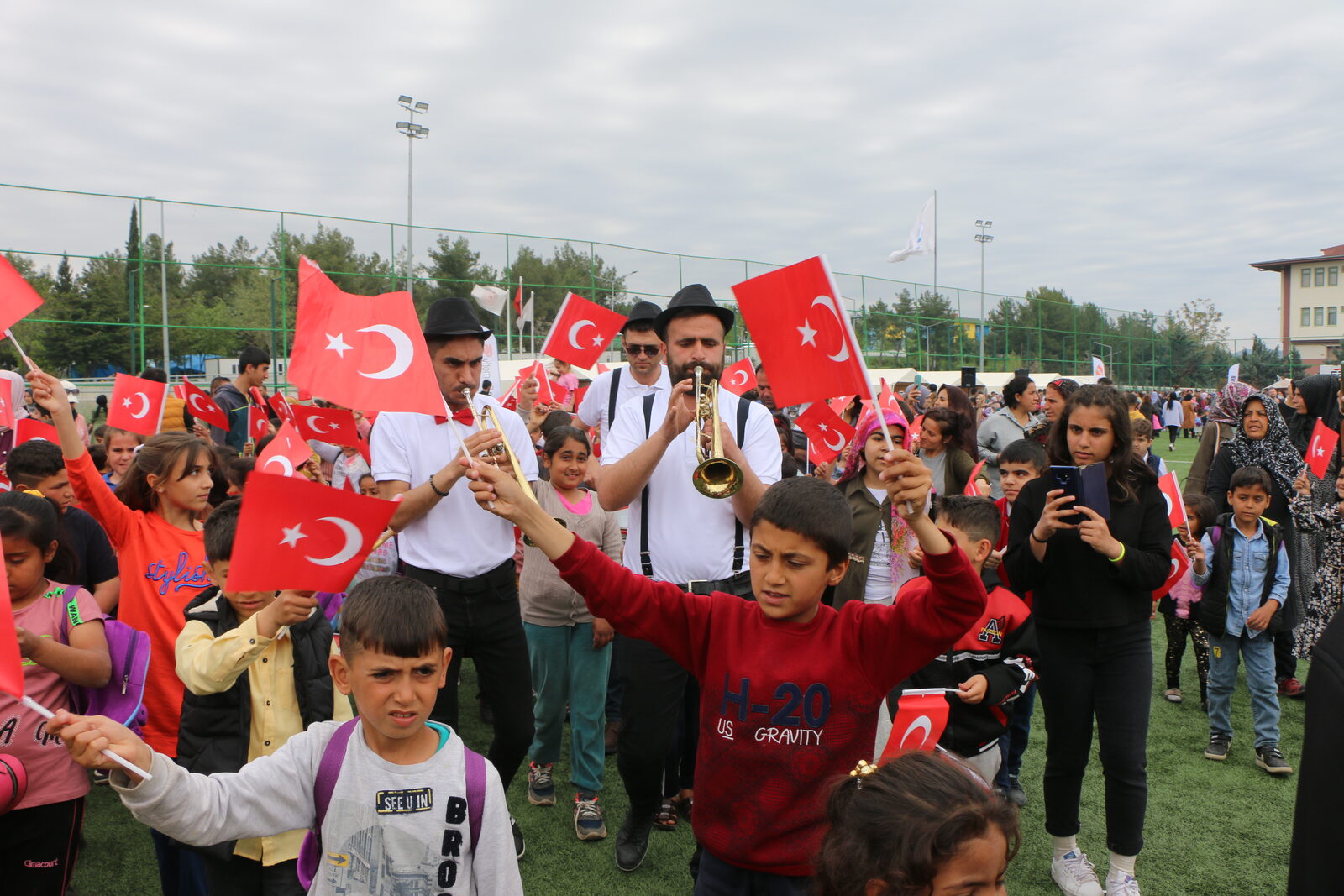 Bando eşliğinde bayrak sallayan çocuklar